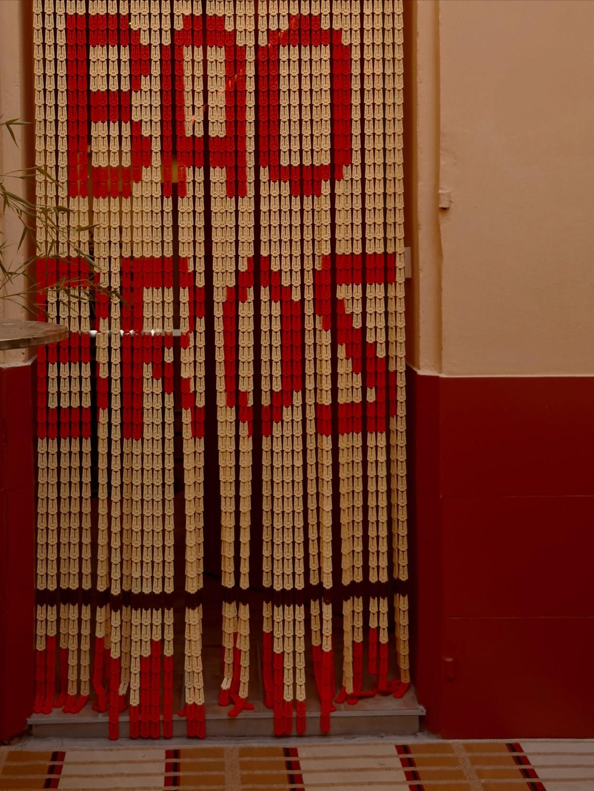 The bead curtain at the door, BAO BROS spelled in red on cream, between the apricot wall and the dark red dado.